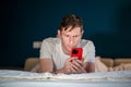 Man uses smartphone lying on bed. Online internet purchases solving business problems conducts chat