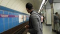 Man uses tablet in subway. Media. Young man uses tablet while waiting for train in metro. Young man is waiting for metro