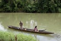 Man ushering a woman passenger on small tiny boat on murky river using paddle