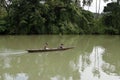 Man ushering a woman passenger on small tiny boat on murky river using paddle