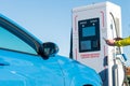 Man using an app on a phone to connect a car to an electric vehicle EV public charging point