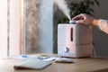 Man using aroma oil diffuser on the table, steam from humidifier, selective focus.Humidification of air in the apartment