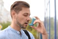 Man using asthma inhaler outdoors. Royalty Free Stock Photo