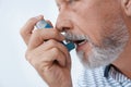 Man using asthma inhaler on white background Royalty Free Stock Photo