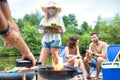 Man using bellows for preparing food in barbecue grill with friends on pier