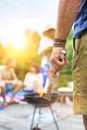 Man using bellows for preparing food in barbecue grill with friends on pier