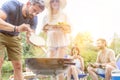 Man using bellows for preparing food in barbecue grill with friends on pier