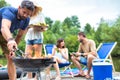 Man using bellows for preparing food in barbecue grill with friends on pier