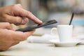 Man using a cell phone on cafe terrace, news paper and coffee