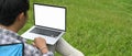 A man is using a computer laptop while sitting over the grass field. Royalty Free Stock Photo