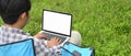 A man is using a computer laptop while sitting over the grass field. Royalty Free Stock Photo