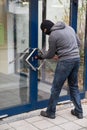 Man Using Crowbar To Open Glass Door Royalty Free Stock Photo