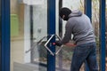 Man Using Crowbar To Open Glass Door Royalty Free Stock Photo