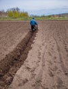 Man using a cultivator in a field on a farm, before planting potatoes Royalty Free Stock Photo