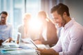 Man using digital tablet while coworker interacting in the background Royalty Free Stock Photo