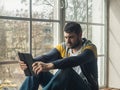 Man using a digital tablet while sitting on the windowsill Royalty Free Stock Photo