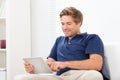 Man using digital tablet on sofa at home Royalty Free Stock Photo