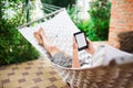 Man using e-book with lorem ipsum text on screen while relaxing in a hammock. Royalty Free Stock Photo