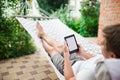 Man using e-book with lorem ipsum text on screen while relaxing in a hammock. Royalty Free Stock Photo