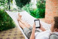 Man using e-book or tablet computer while relaxing in a hammock Royalty Free Stock Photo