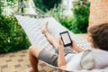 Man using e-book or tablet computer while relaxing in a hammock Royalty Free Stock Photo