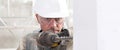 Man using an electric pneumatic drill making a hole in wall, professional construction worker with safety hard hat,, gloves and Royalty Free Stock Photo