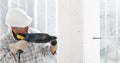 Man using an electric pneumatic drill making a hole in wall, professional construction worker with safety hard hat, hearing Royalty Free Stock Photo