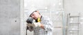 Man using an electric pneumatic drill making a hole in wall, professional construction worker with safety hard hat, hearing Royalty Free Stock Photo