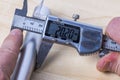 Man is using electronic caliper to measure size of aluminum pipe.