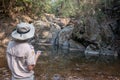 A man using electronic devices to explore an arid waterfall. naam dtok sa-won-hom wang-nam-kieow Nakhon Ratchasima. thailand