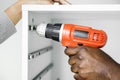 Man using electronic drill install cabinet