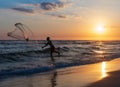 A man using a fishing net during the sunset on a summer day at Praia da Barra da Tijuca Beach, Rio de Janeiro city. Brazil.