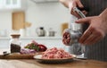 Man using hand meat grinder in kitchen, closeup