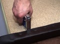 Man using hand-tool stapler and leatherette upholstering particle board