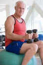 Man Using Hand Weights On Swiss Ball At Gym Royalty Free Stock Photo