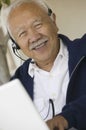 Man using headset and laptop smiling (portrait)