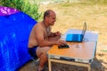 Man using his laptop sitting at a folding picnic table in a camping. Working while traveling. Freelance work. Royalty Free Stock Photo