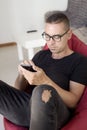 Man using his smartphone sitting in bean bag chair Royalty Free Stock Photo