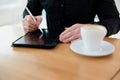 Man using his tablet with stylus. opy space screen on gadget. Cut close up view of man in black clothes sitting with cup of coffee Royalty Free Stock Photo