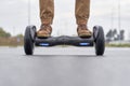 Close up of man using hoverboard on asphalt road. Feet on electrical scooter outdoor, front view