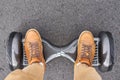 Close up of man using hoverboard on asphalt road. Feet on electrical scooter outdoor, top view Royalty Free Stock Photo