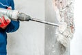 Man using a jackhammer to drill into wall