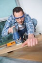 Man using jigsaw to cut through floorboard Royalty Free Stock Photo