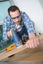Man using jigsaw to cut through wooden floorboard Royalty Free Stock Photo
