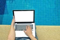 Man using laptop computer beside swimming pool