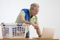 Man Using Laptop While Doing the Laundry Royalty Free Stock Photo