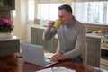 Man using laptop while having cup of coffee in living room Royalty Free Stock Photo