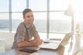 Man using laptop on his workplace. sitting, smiling, looking at camera. Royalty Free Stock Photo