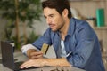 Man using laptop and holding bankcard