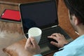 Man is using laptop with holding cup in hand Royalty Free Stock Photo